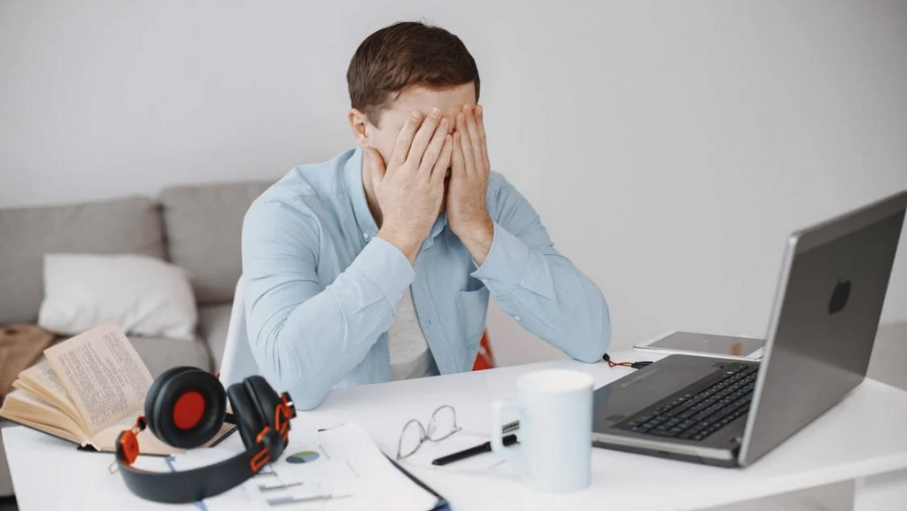 a man sitting at a desk with his hands over his face