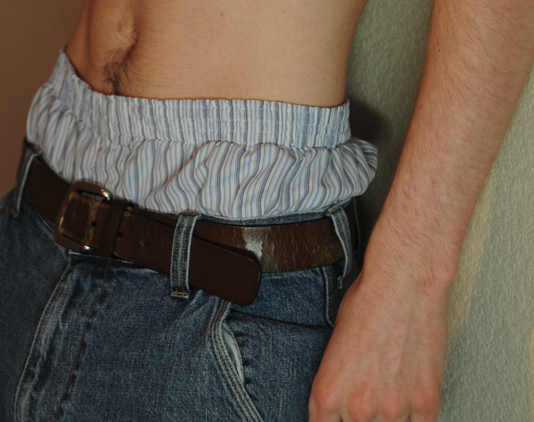 a man wearing blue jeans and a brown belt