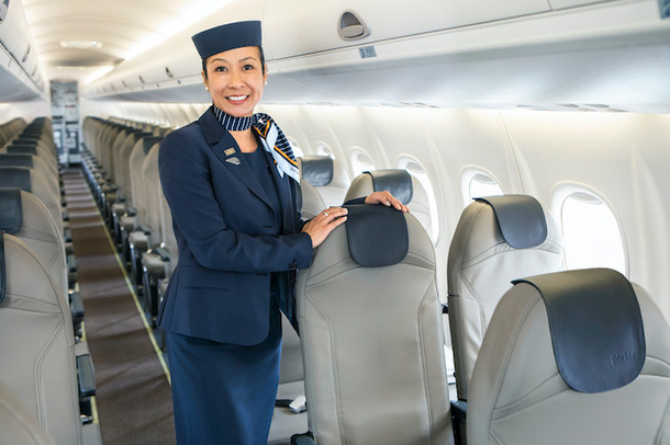 a woman in a uniform standing next to a chair in an airplane