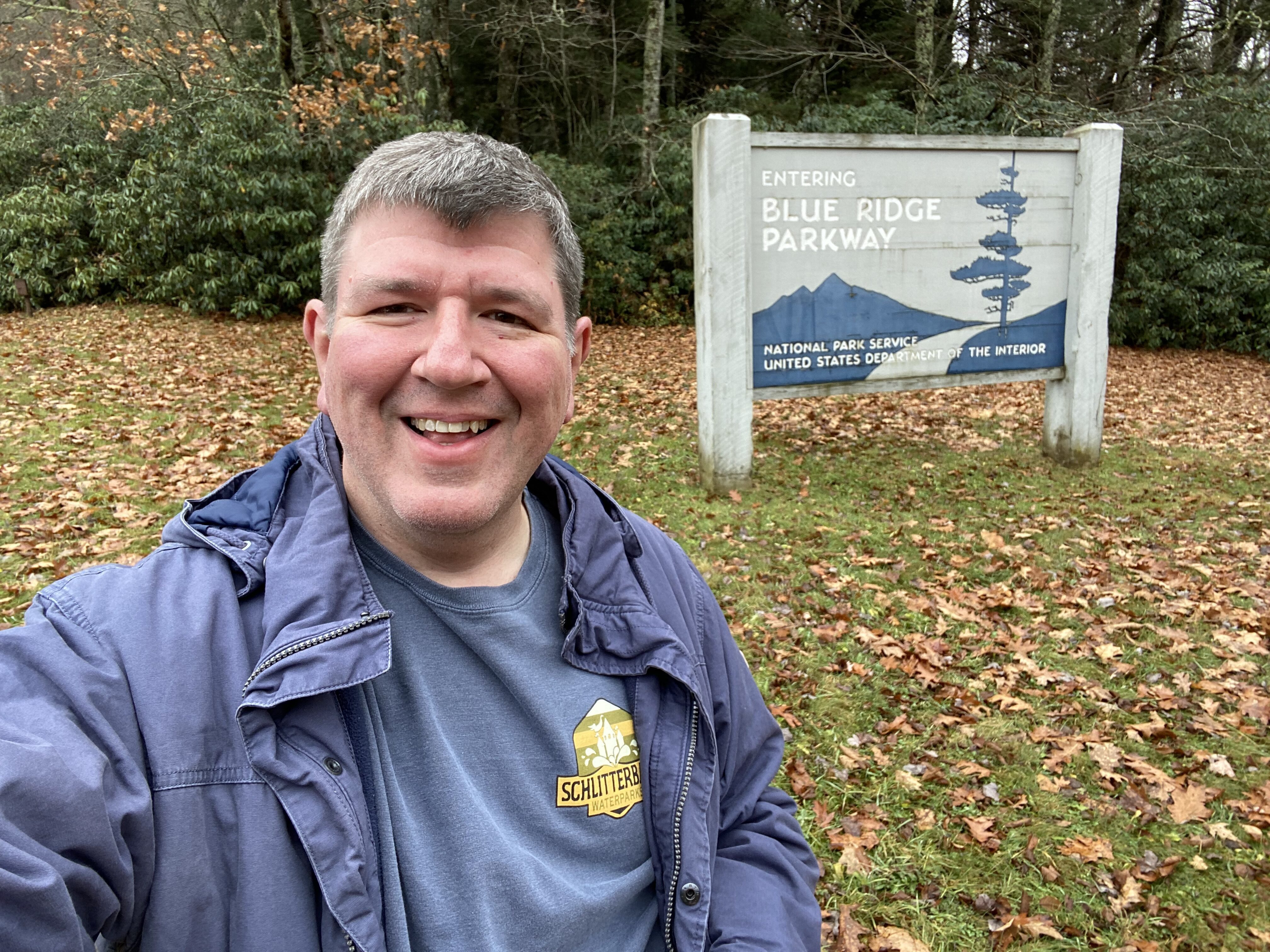 a man smiling in front of a sign