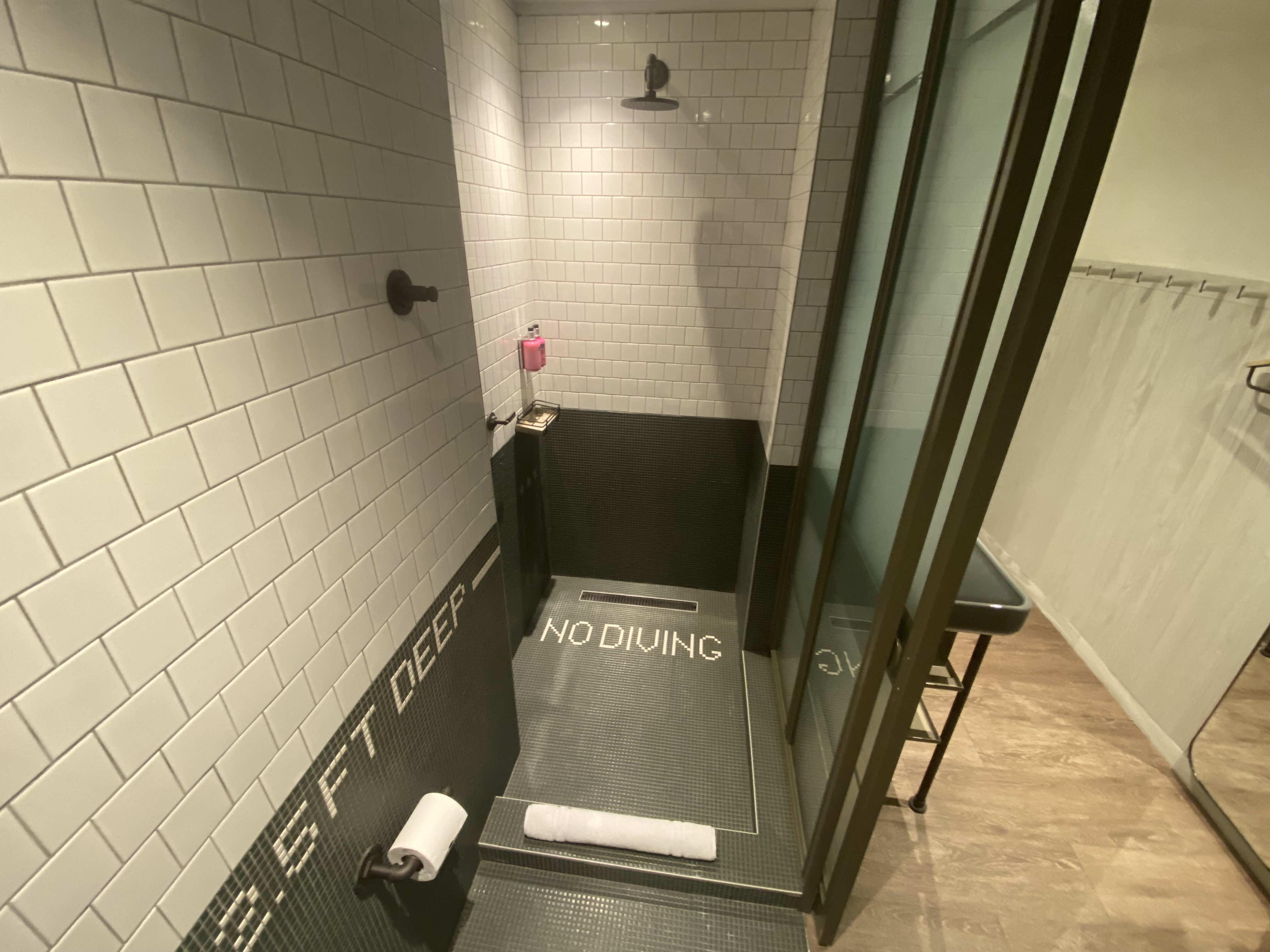 a shower with a black mat and white tile walls