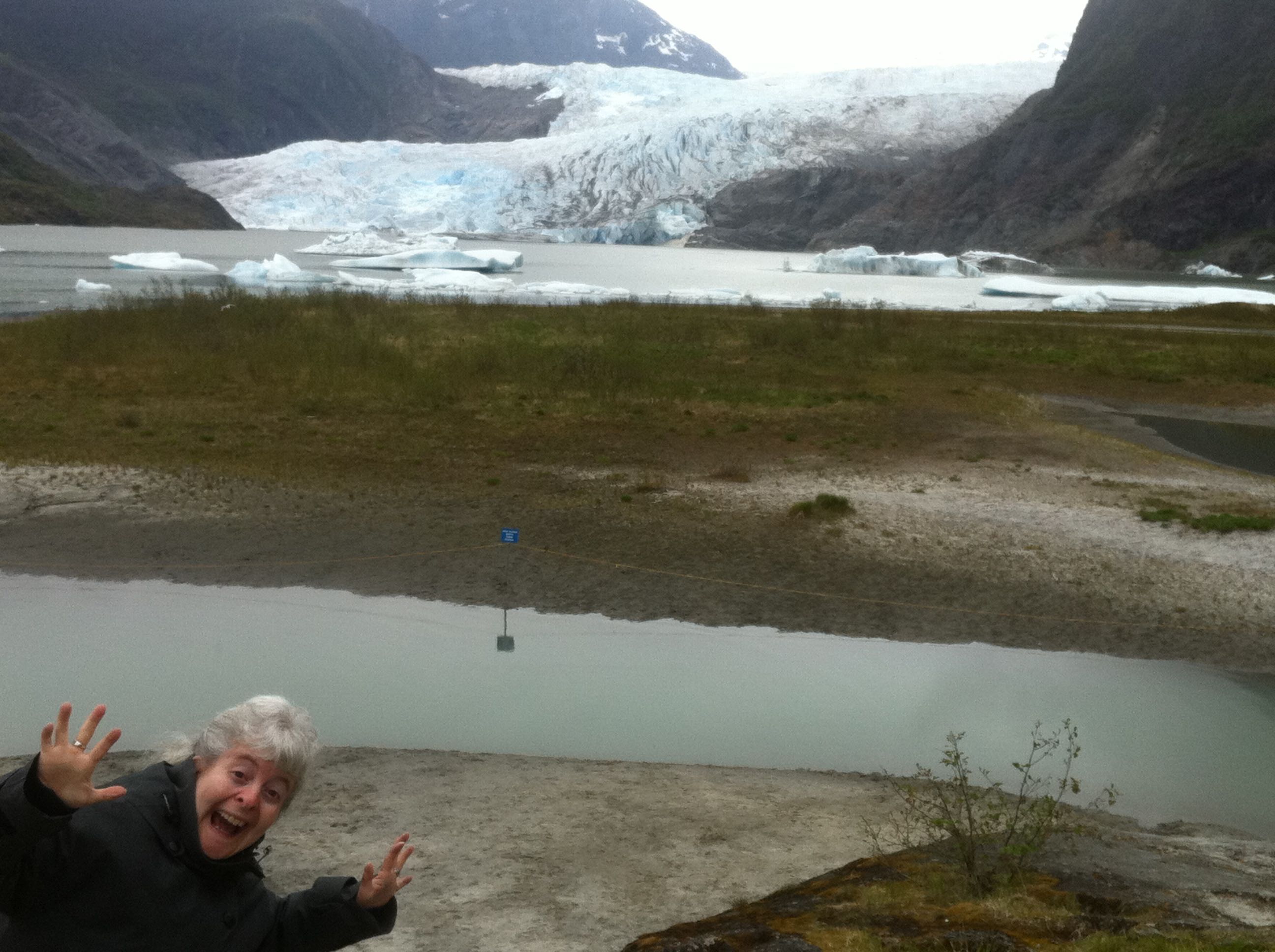 a woman standing in front of a river with icebergs in the background