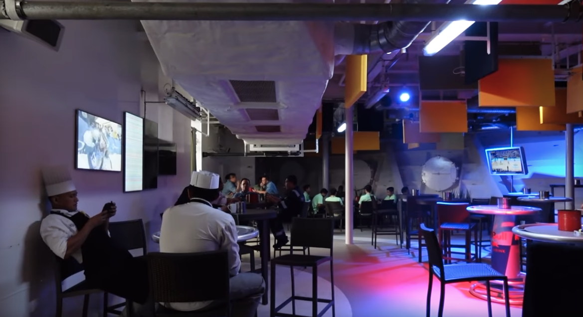 a group of people sitting at tables in a room with blue lights