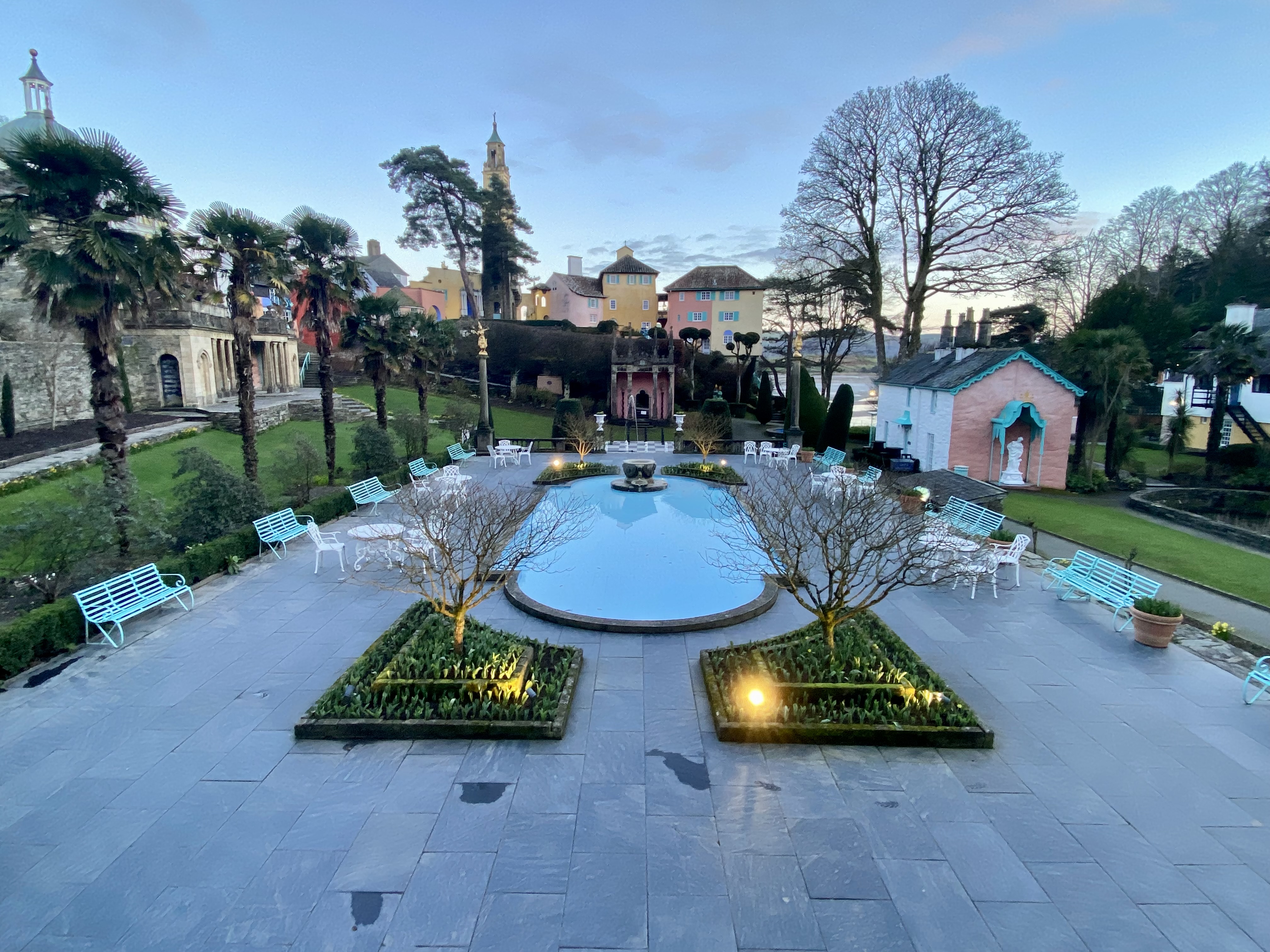 a pool with a fountain and chairs in a courtyard