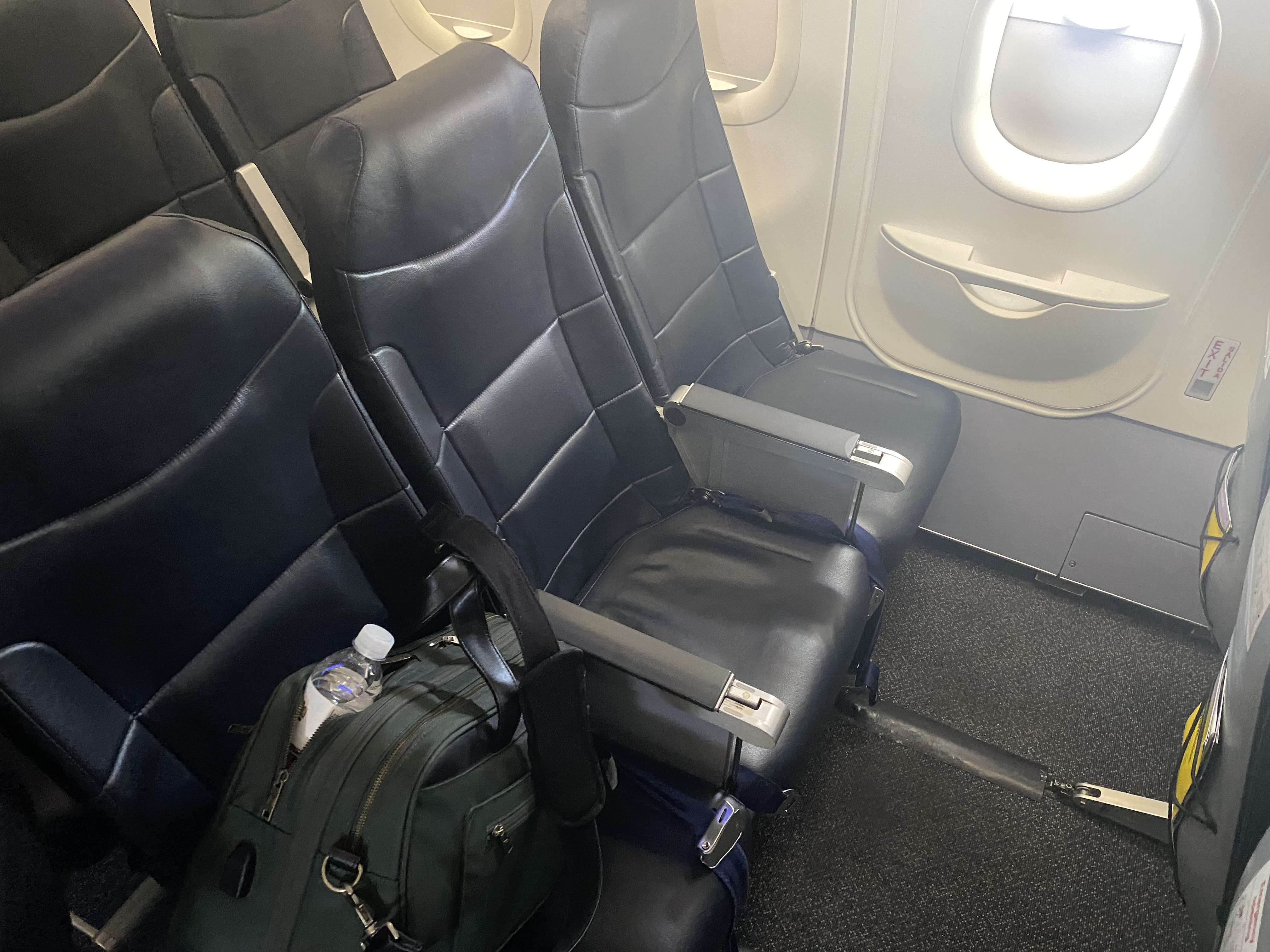 a seat in an airplane with a bag and a bottle