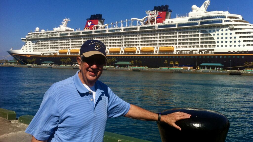 a man in a blue shirt and hat standing next to a ship