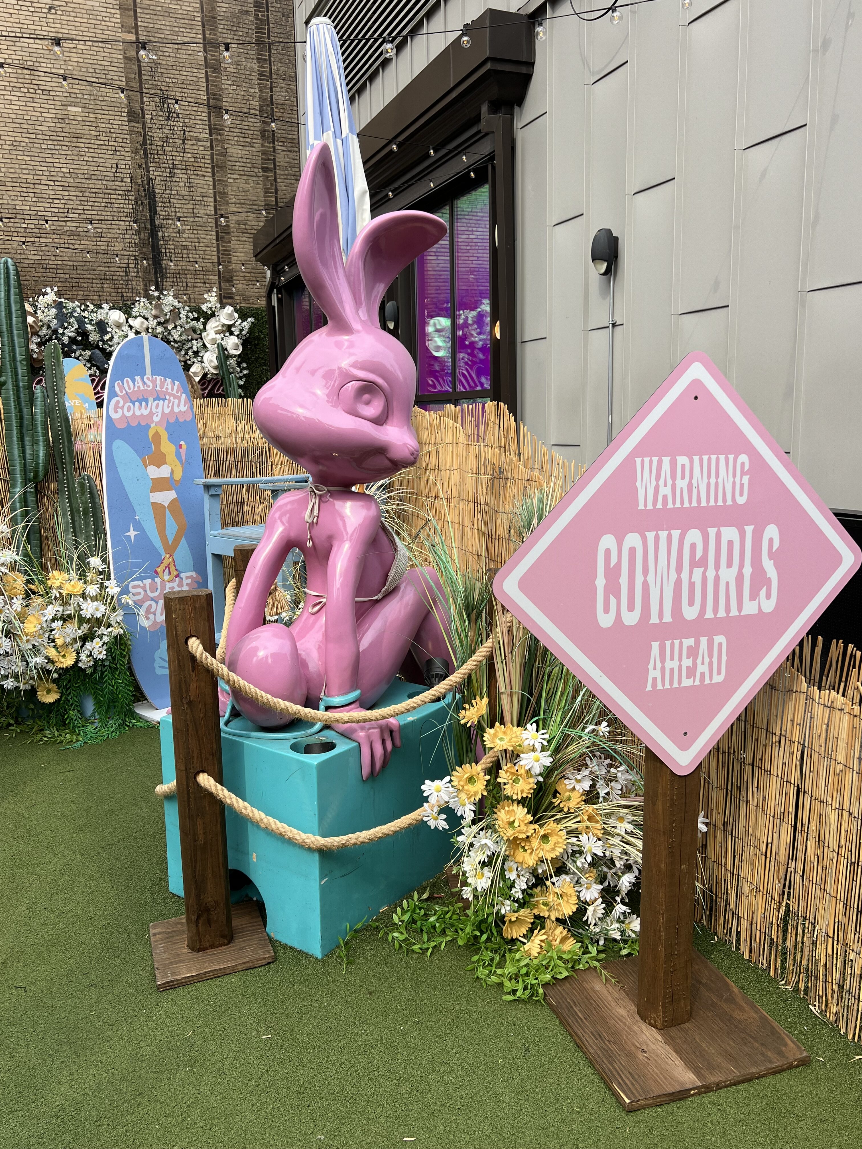 a pink bunny statue in front of a sign