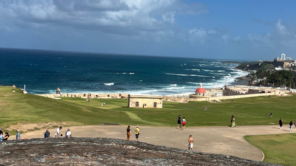 a group of people on a grassy field by the ocean