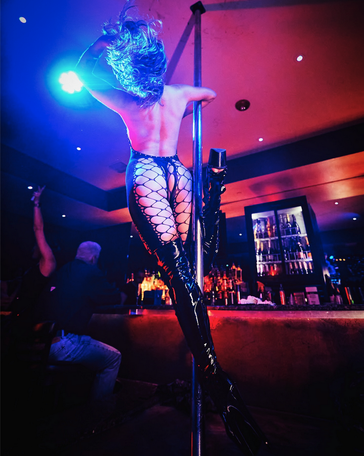 a woman in a fishnet outfit and boots dancing on a pole