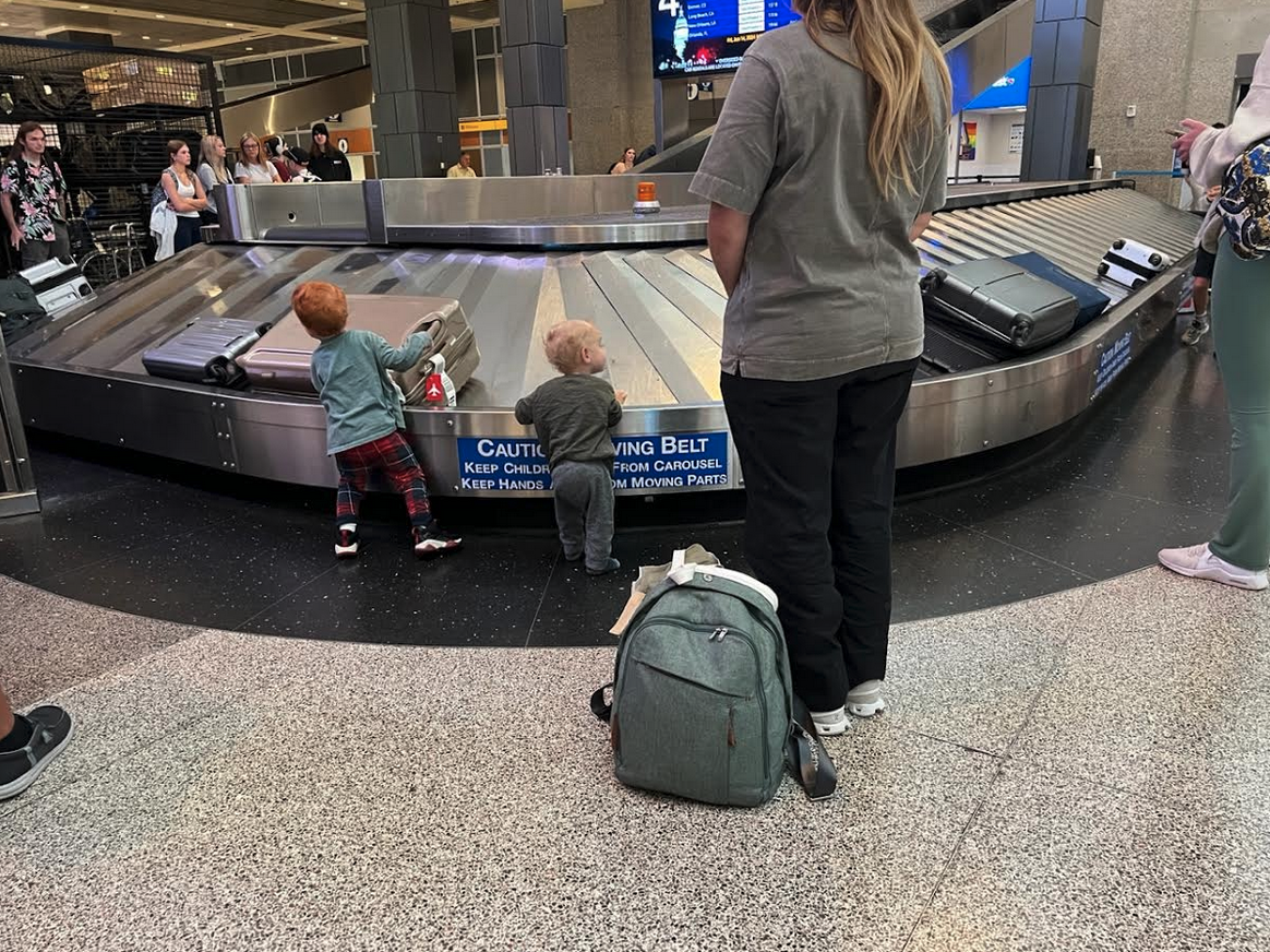 a woman and two children at a baggage claim area