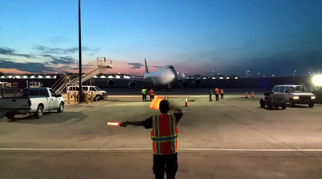 a man in a safety vest holding a red light up to a plane