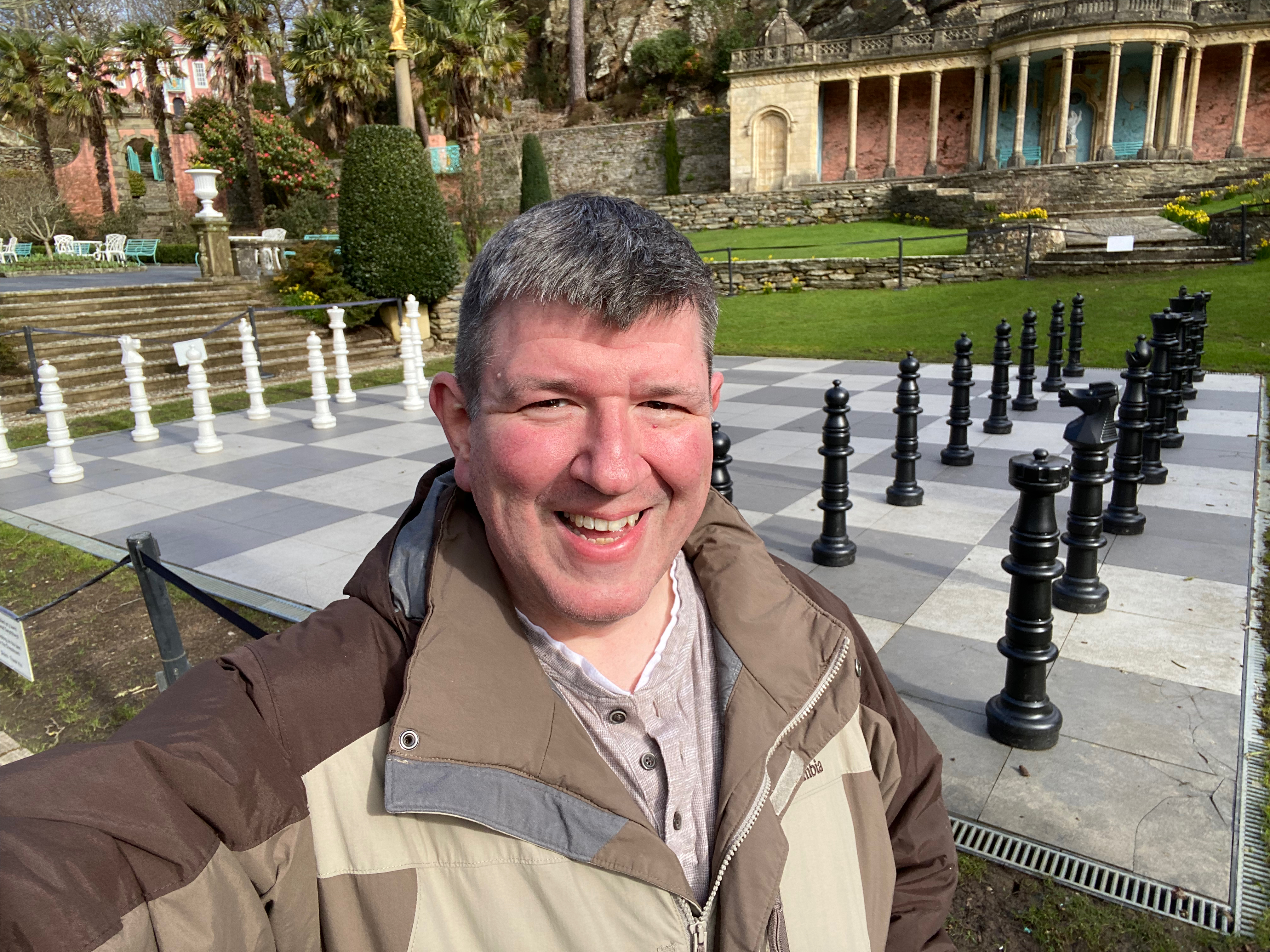 a man taking a selfie in front of a chess board