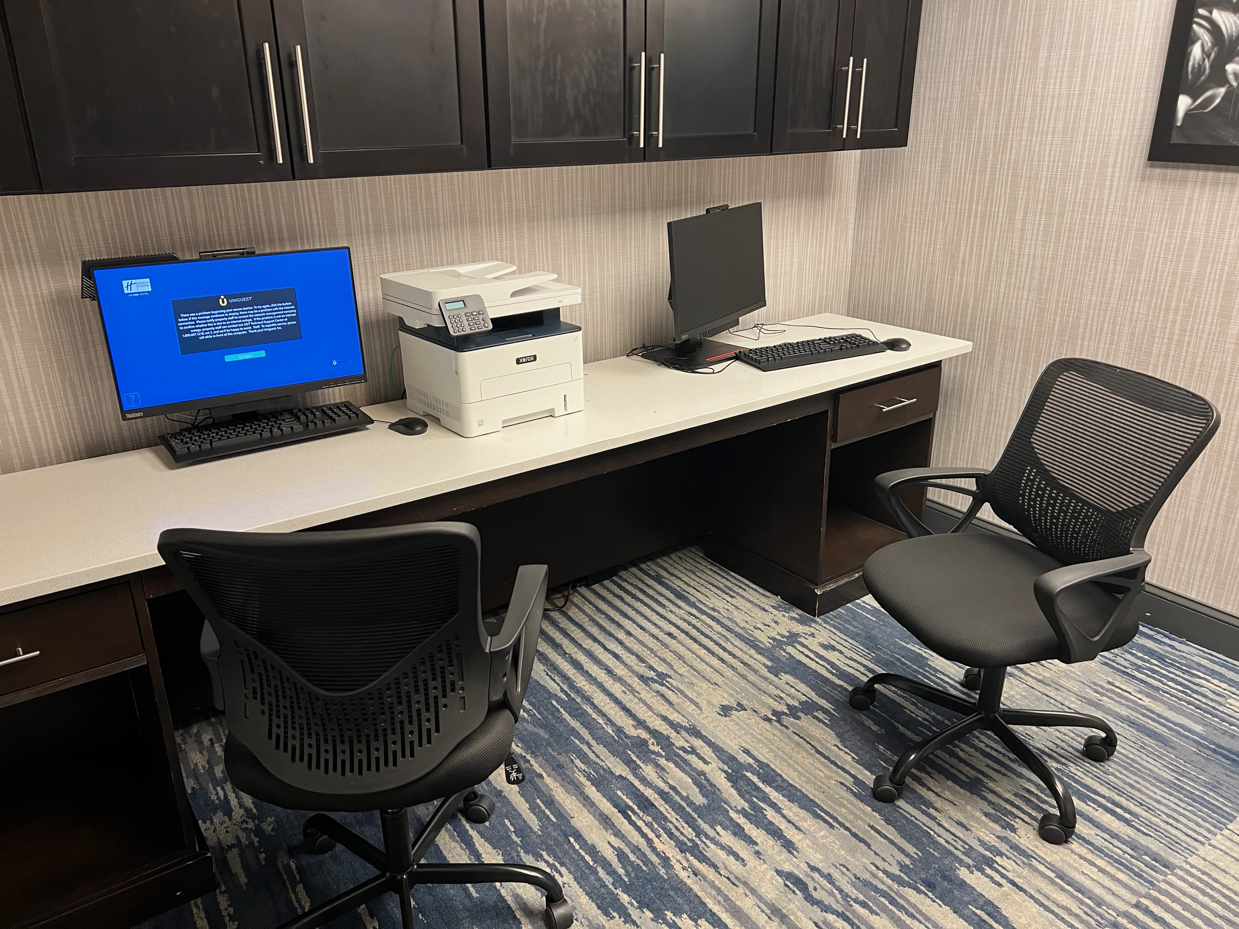 a desk with a computer and chairs