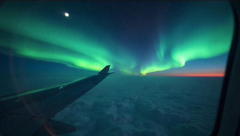 an airplane wing with the northern lights in the sky