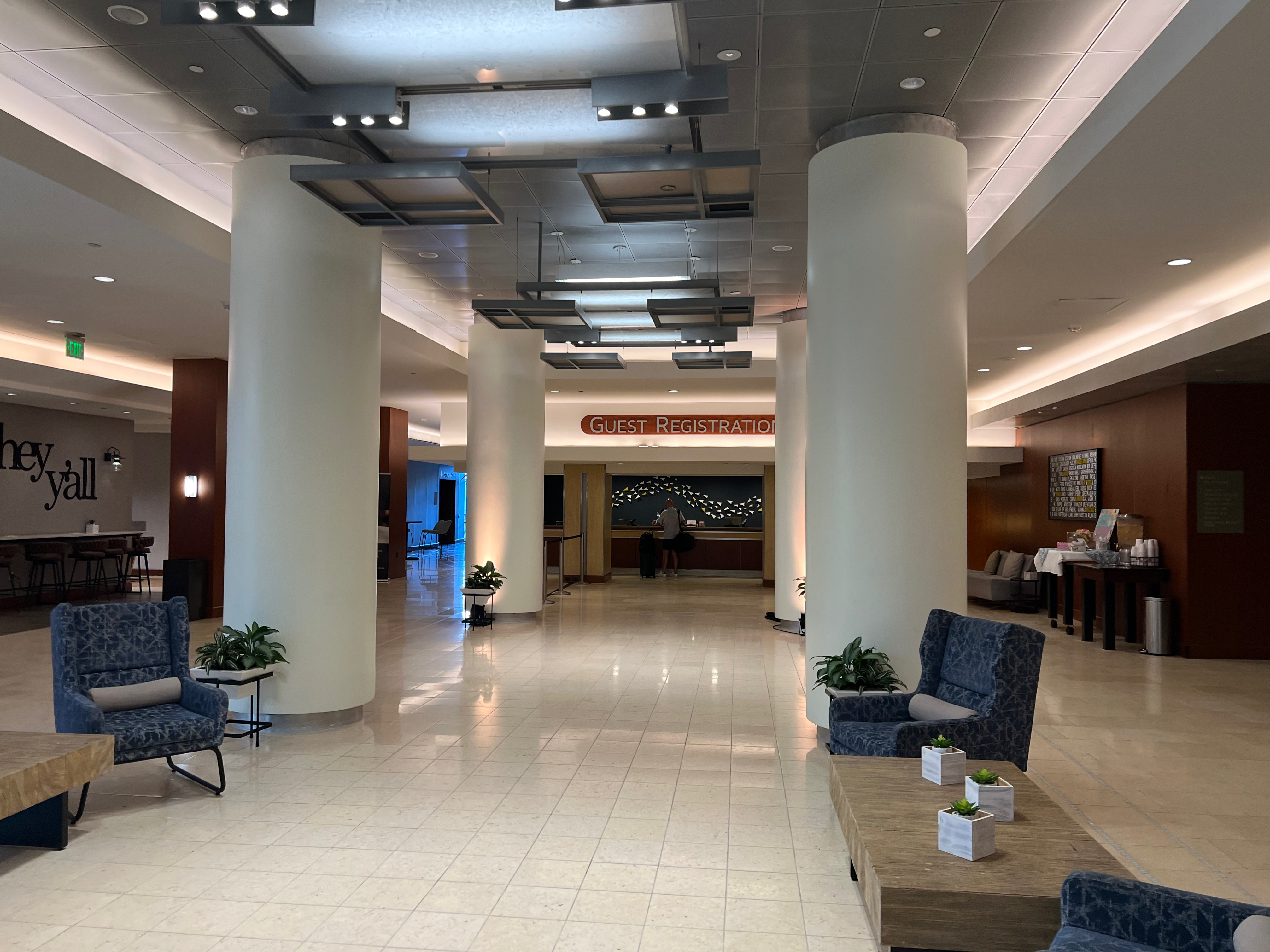 a lobby with a large white column and blue chairs