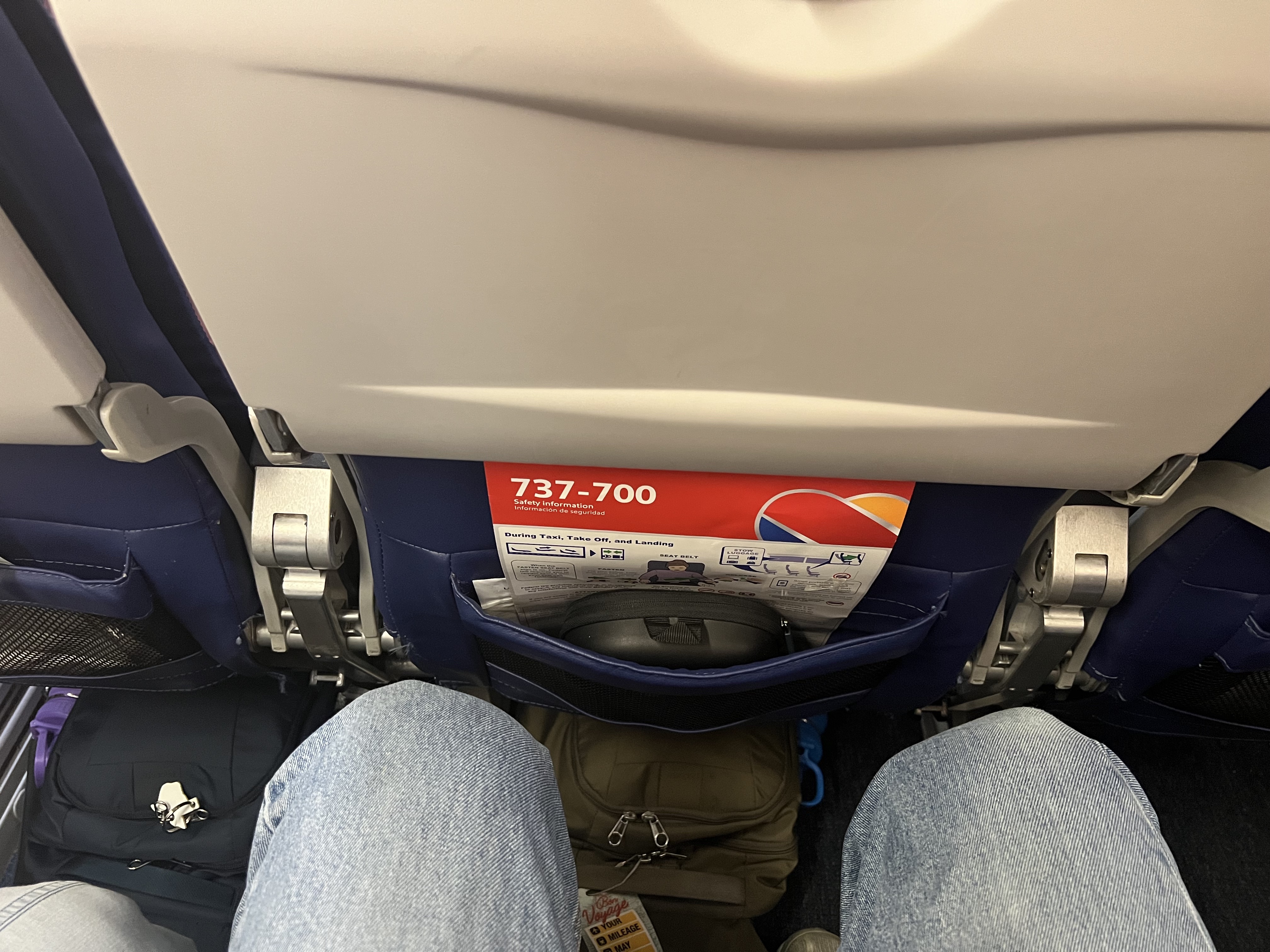 a person's legs and a bag under a seat