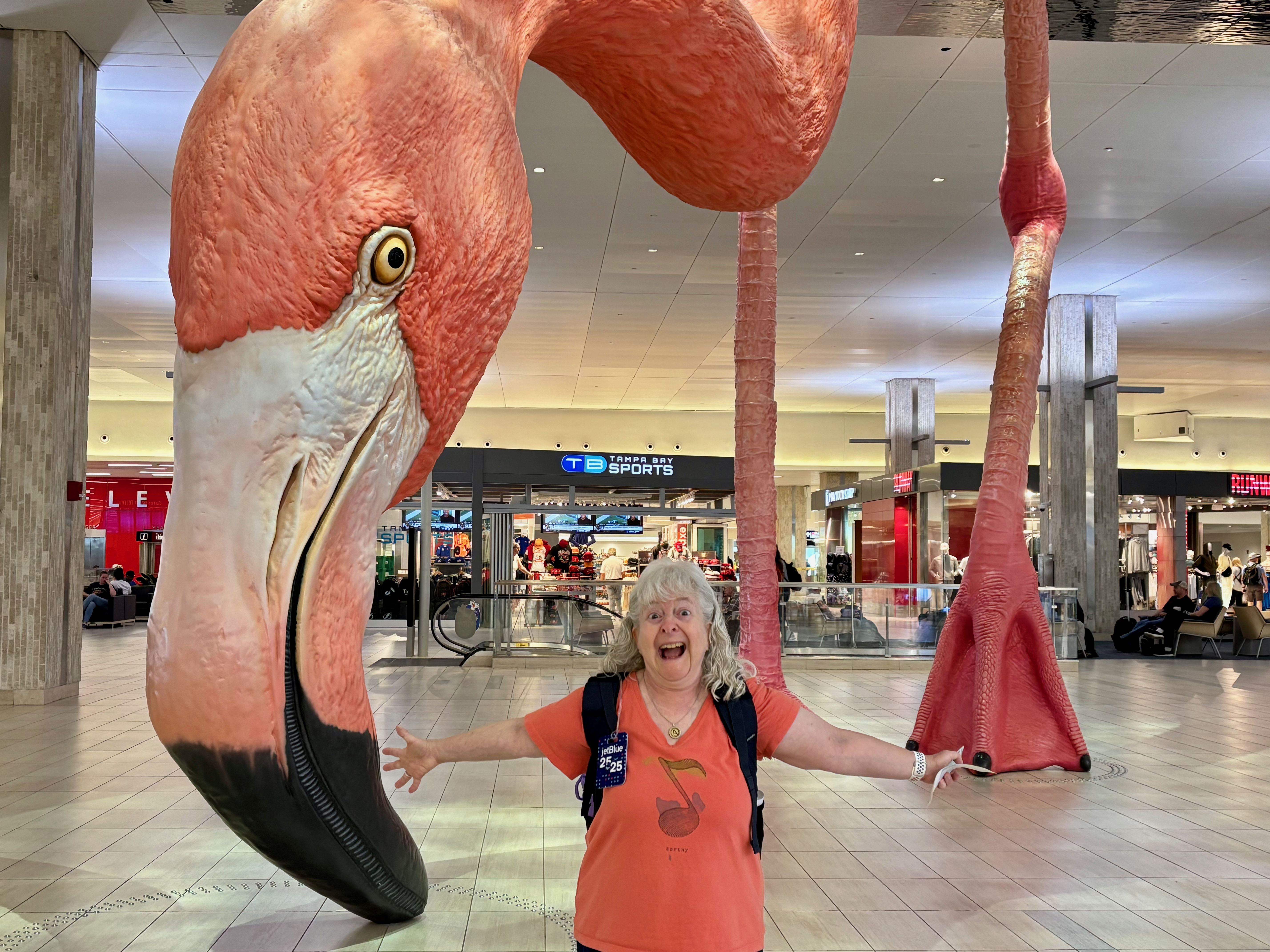a woman standing in front of a large flamingo statue