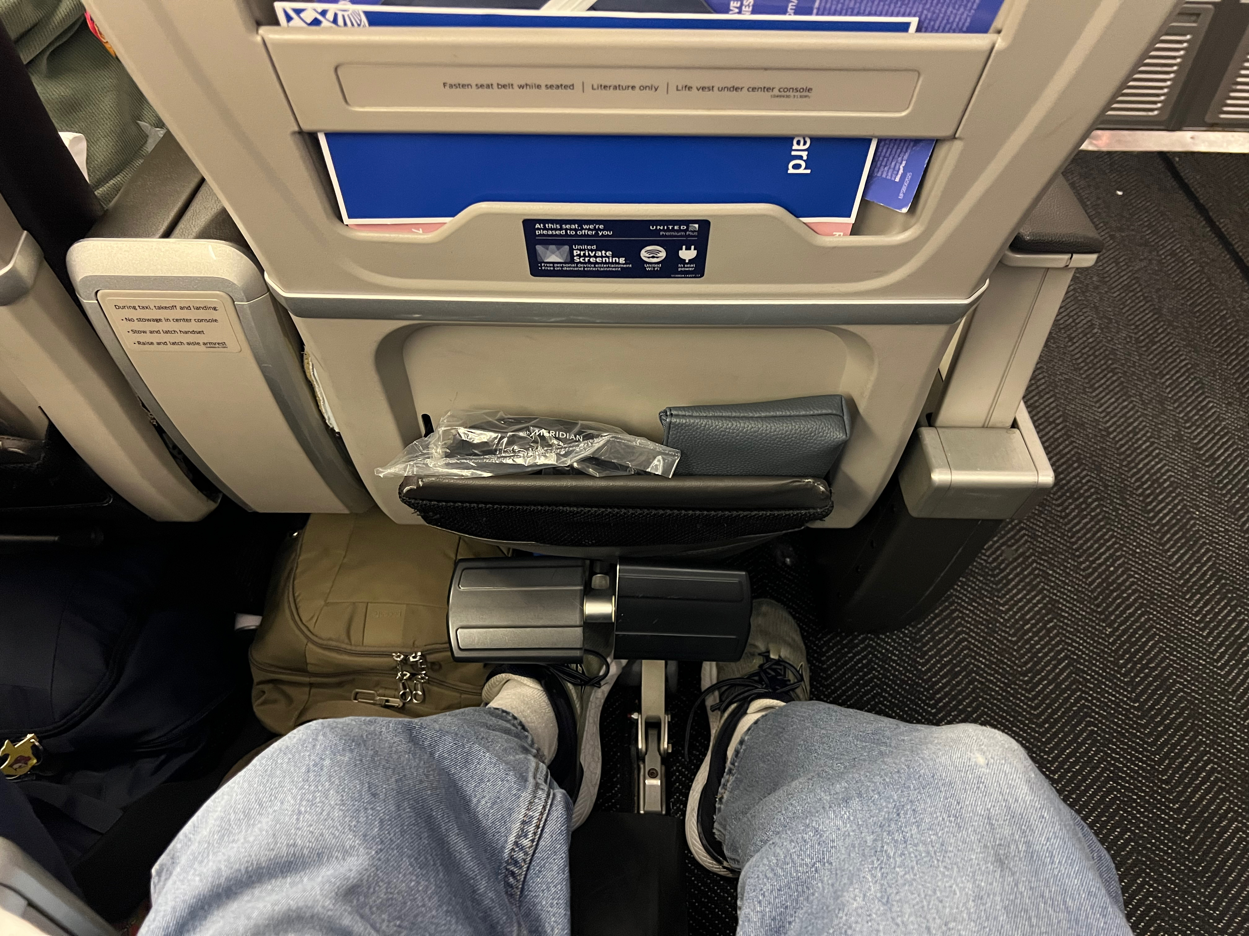 a person's legs in a seat with a bag and a seat belt