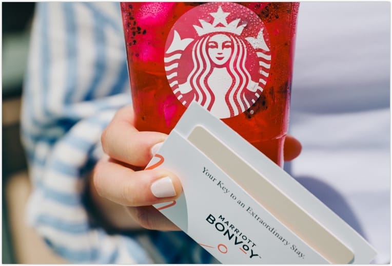 a hand holding a red drink and a card