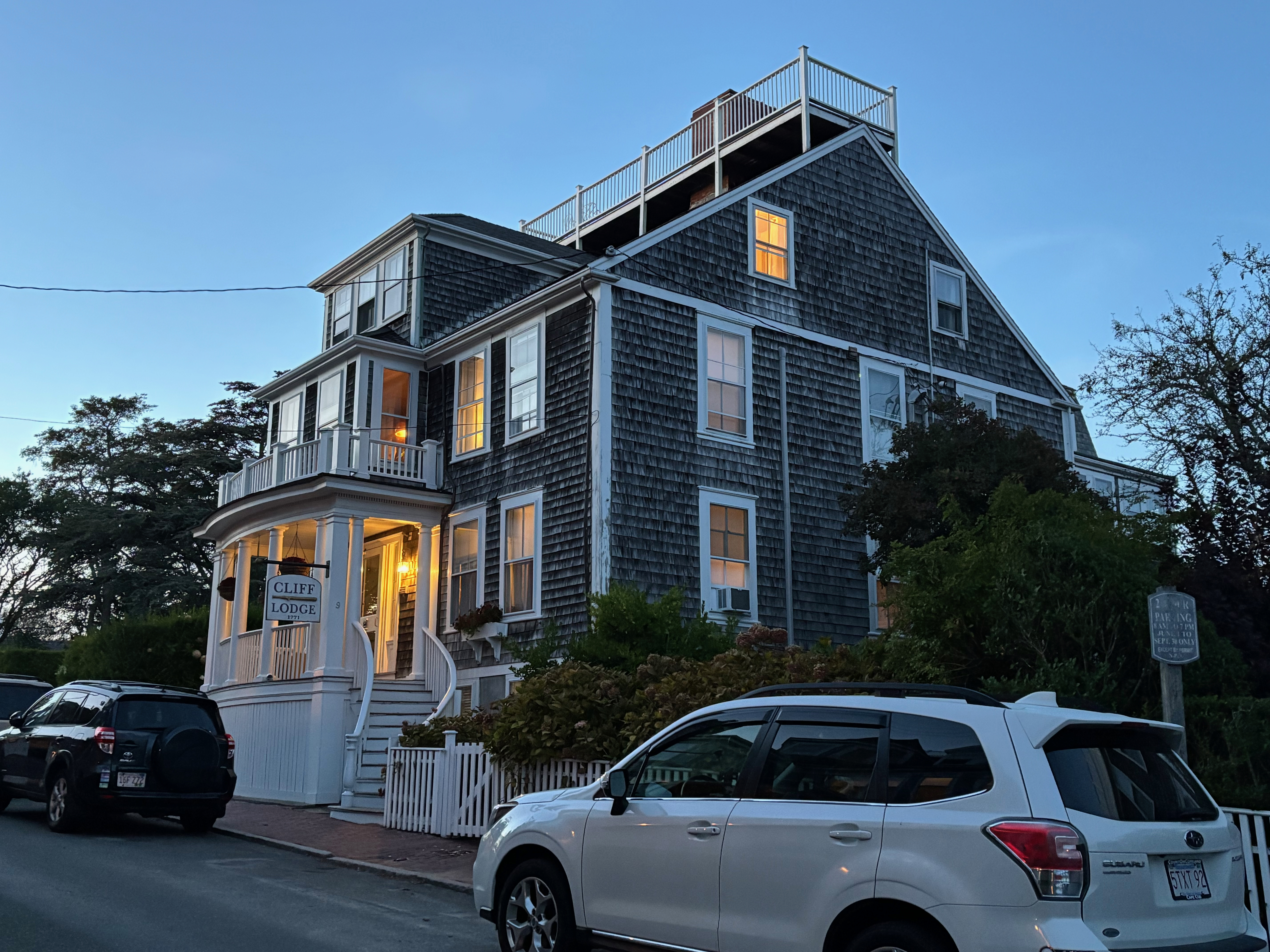 a house with a balcony and a car parked on the side of the road
