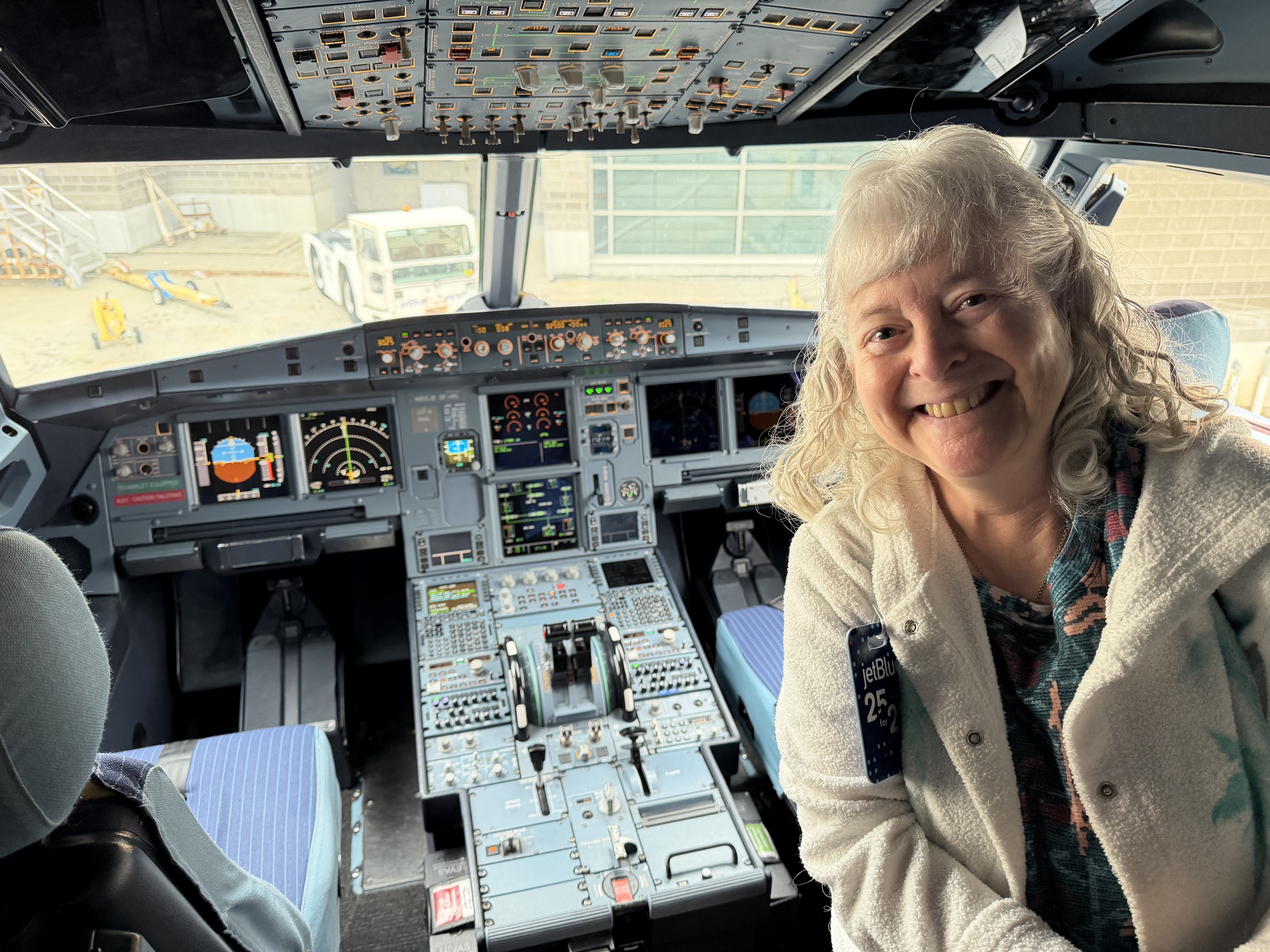 a woman smiling in a cockpit of an airplane