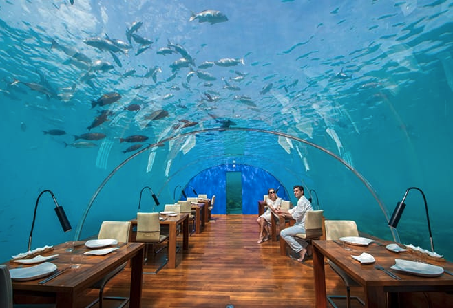 Couple dining inside an underwater tunnel at Conrad Maldives