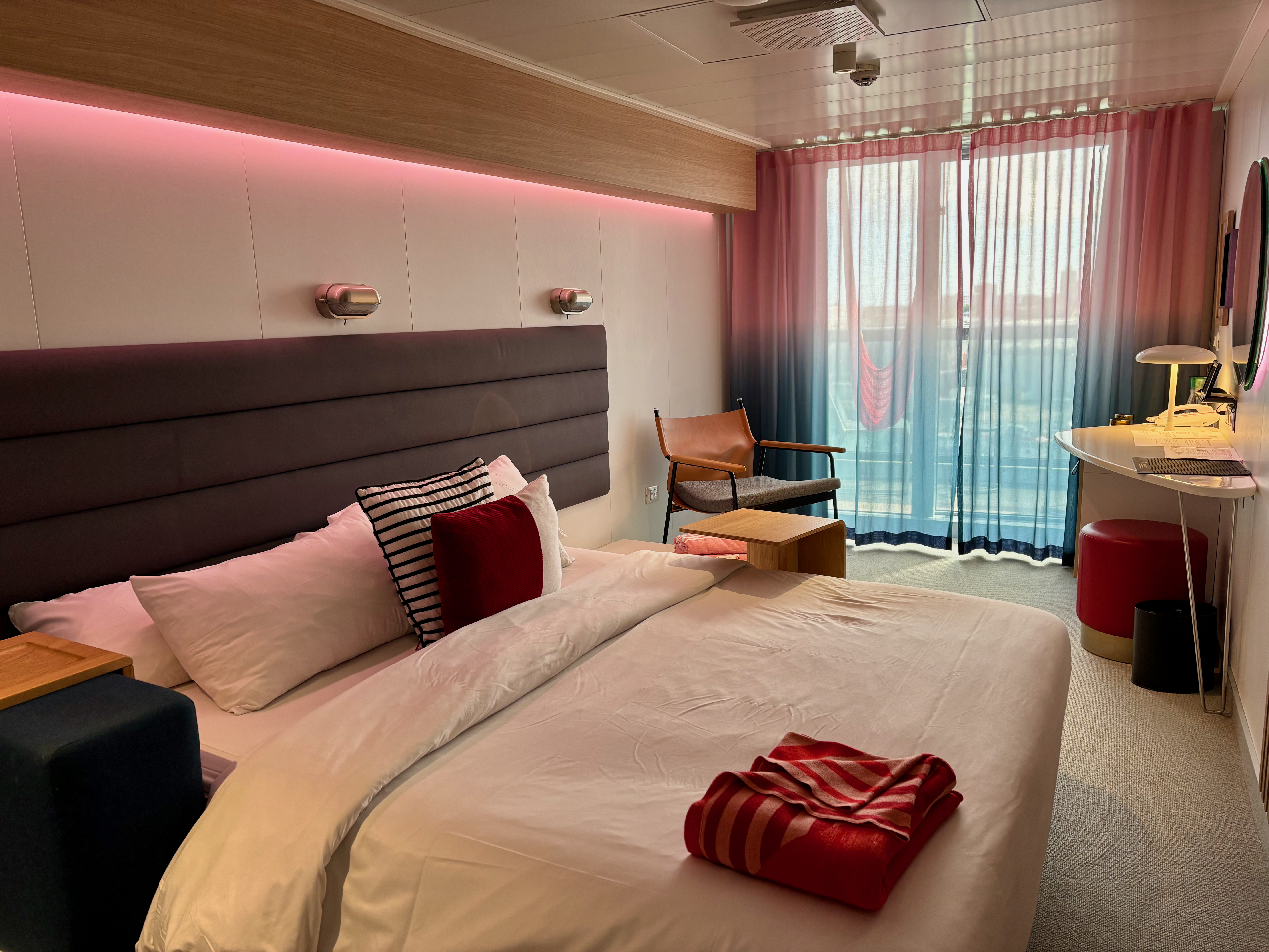 a bed with a chair and a table in a room with curtains