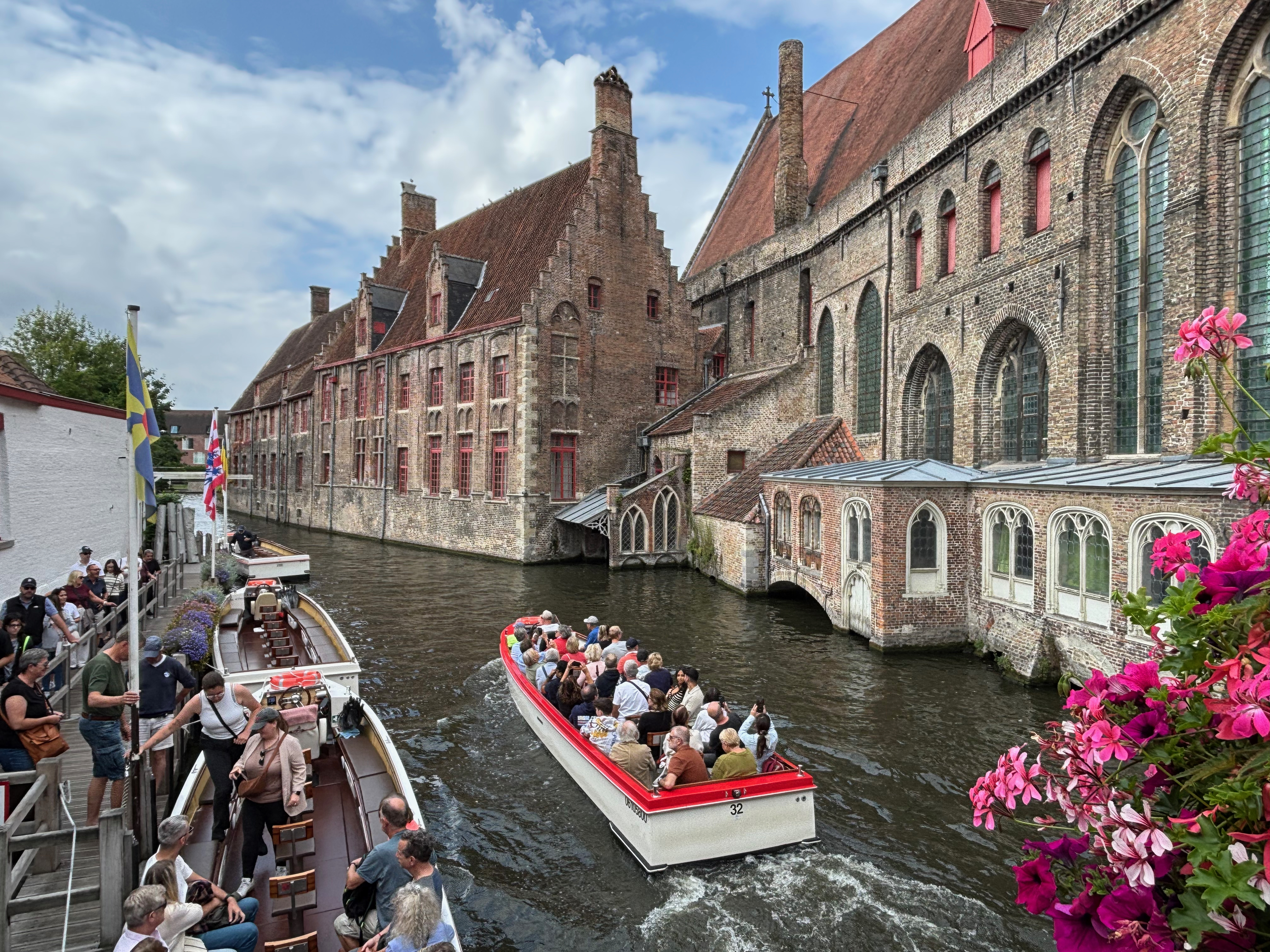 a boat with people on it in a canal with buildings and Bruges