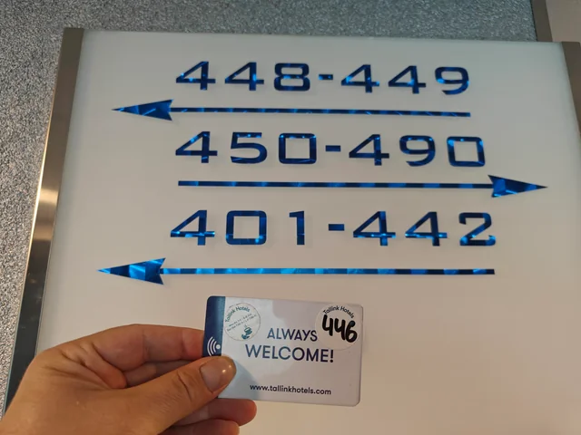 a hand holding a card next to a sign