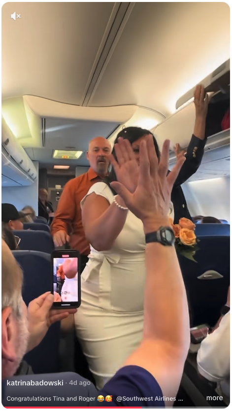 a woman in a white dress waving in an airplane