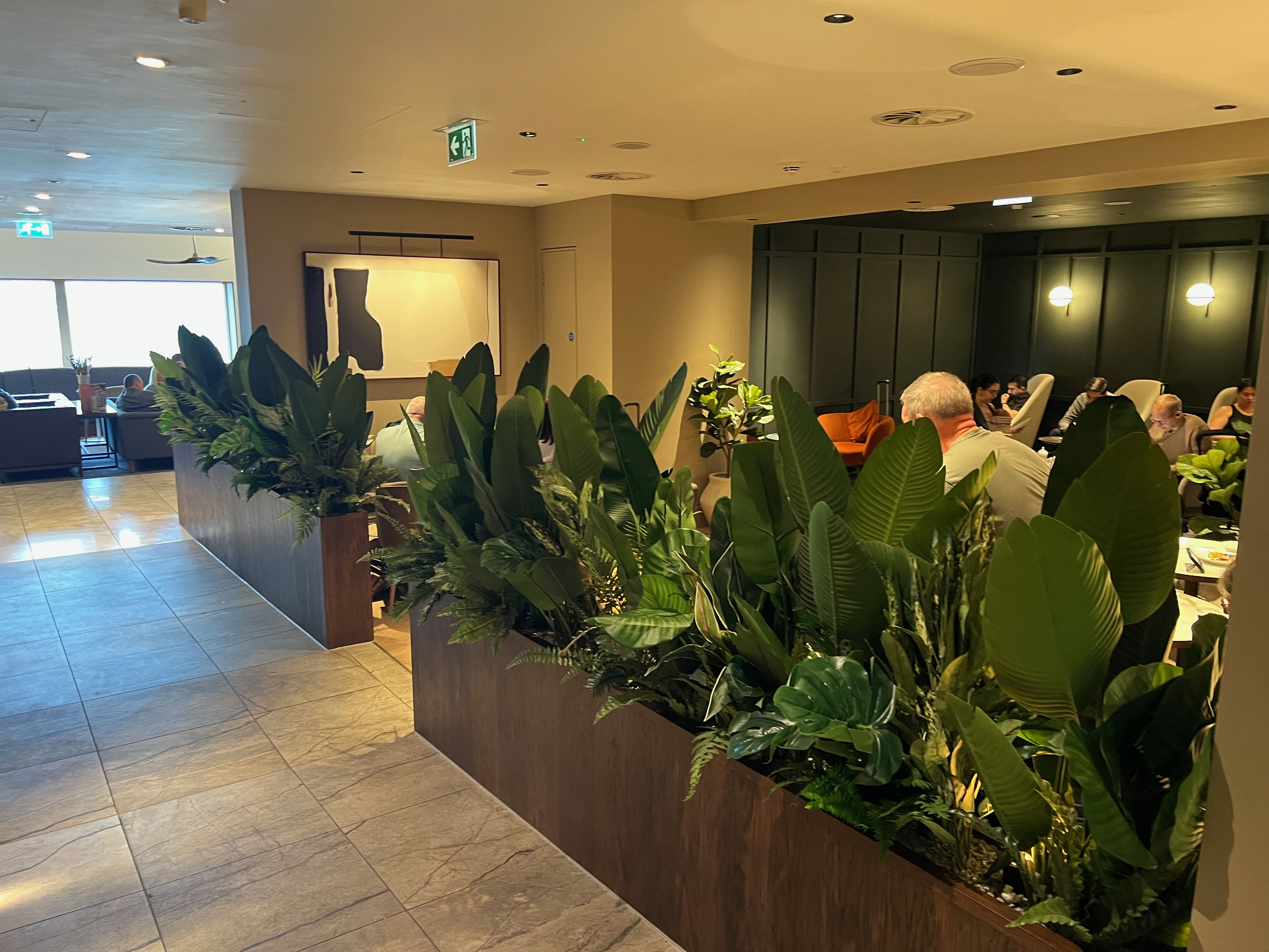Seating area inside the lounge with plants and travelers relaxing