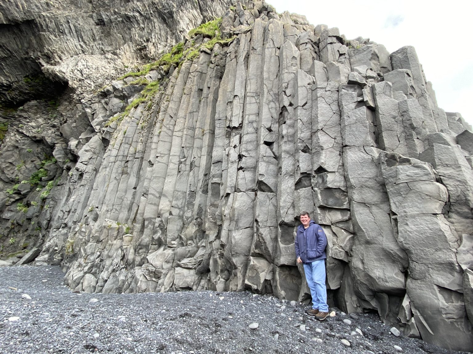 a man standing in front of a rock wall