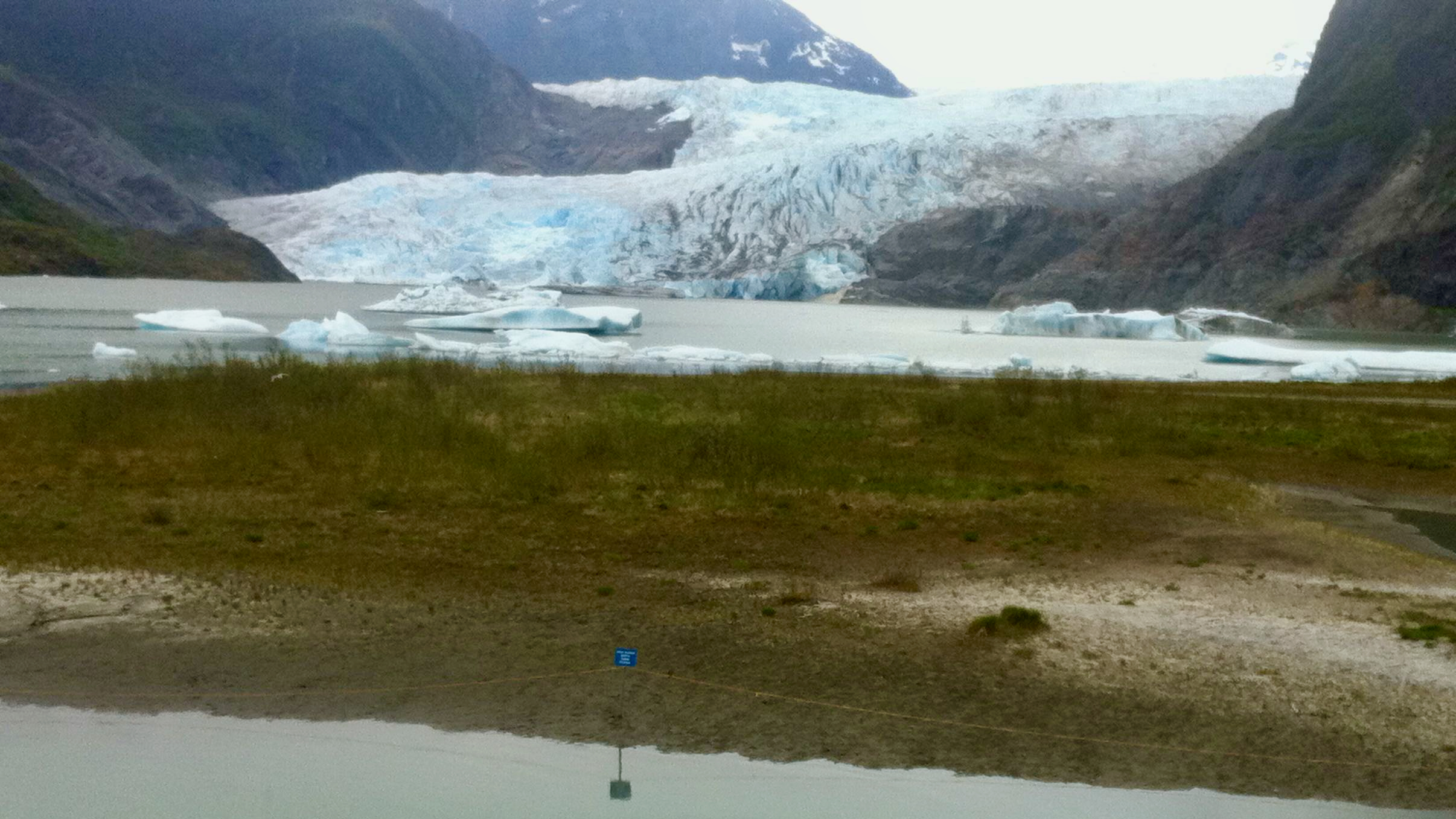 A glacier flowing into a lake in Alaska with floating ice chunks in the foreground