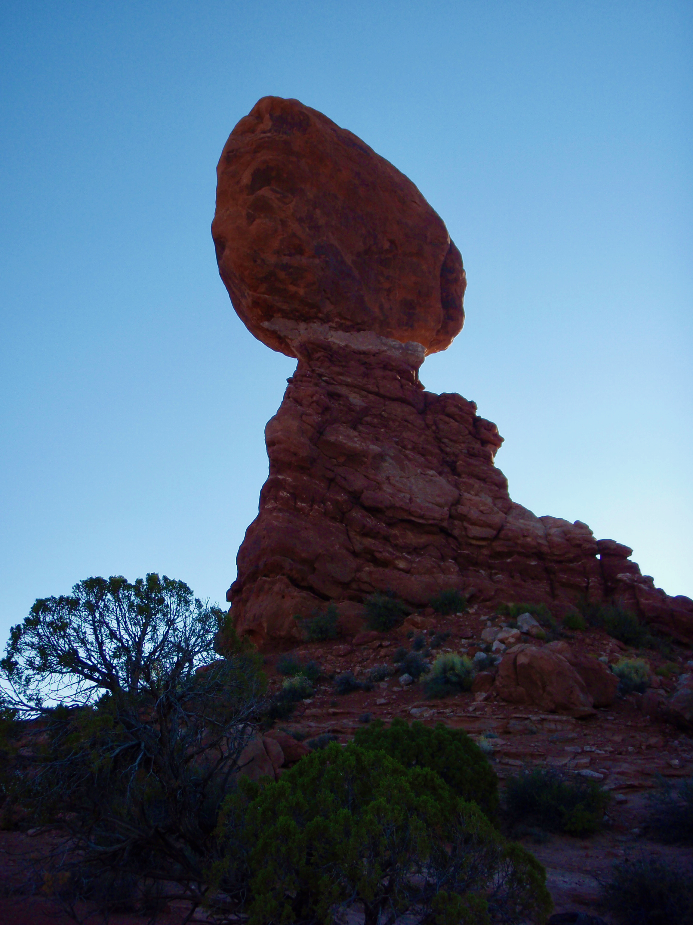 Balancing Rock formation in Arches National Park silhouetted against a blue sky