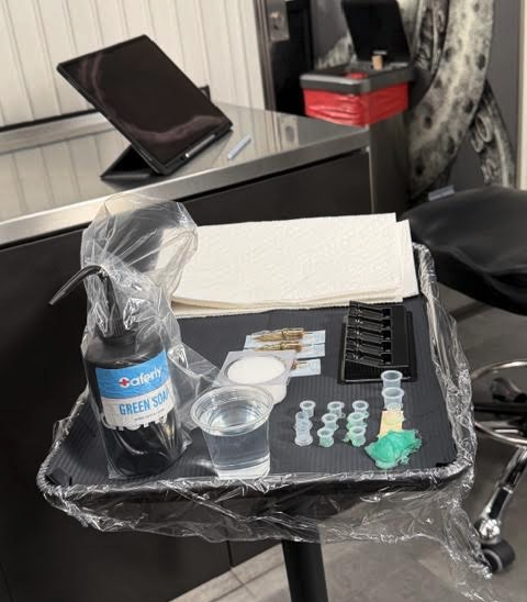 a tray with a black tray and a plastic bag with a bottle of green liquid and a cup of liquid in it