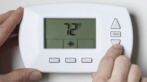 a person holding a white thermostat