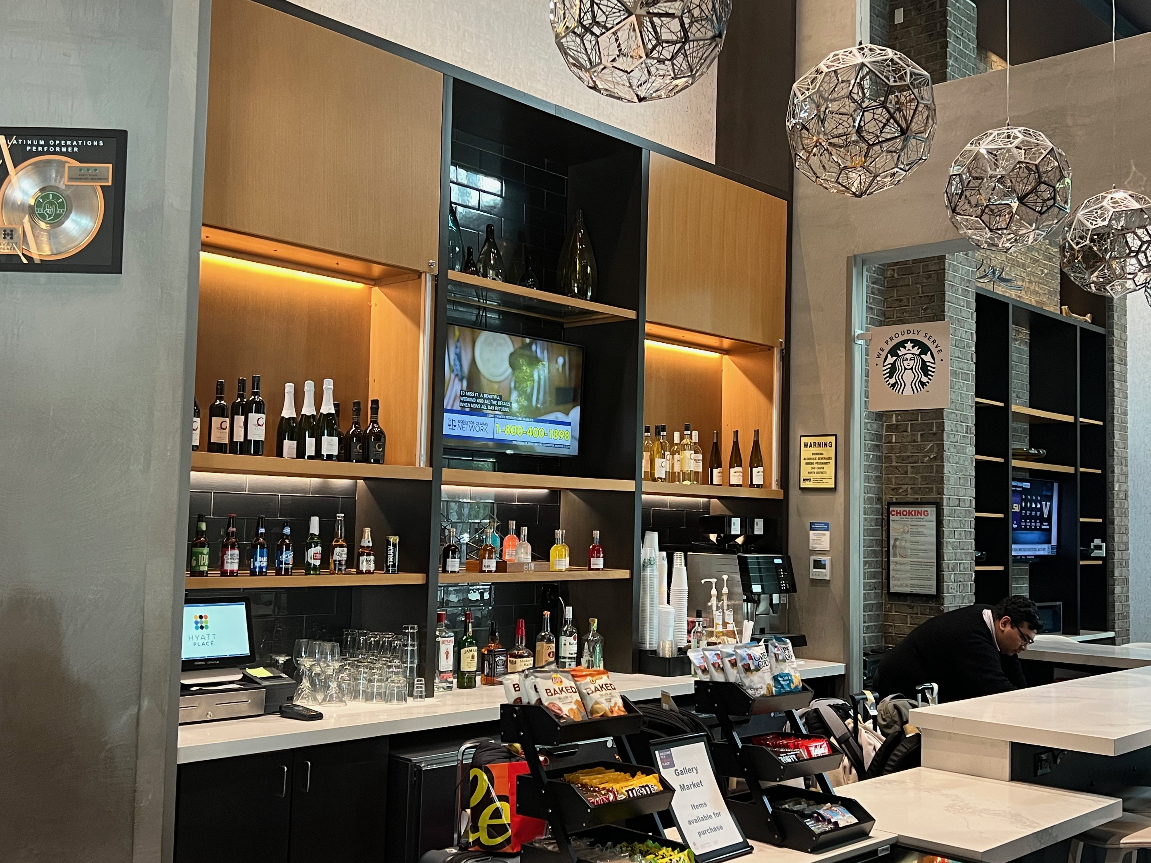 a bar with shelves of liquor and a man sitting at the counter